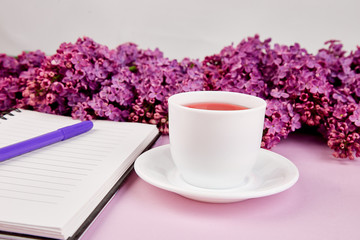 Cup of tea, diary and bouquet  lilac