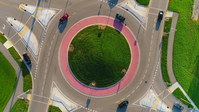 Early morning rush hour at busy city roundabout, time lapse aerial view.
