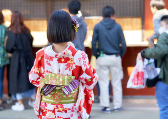 Obraz premium Young girl wearing Japanese kimono standing in front of Sensoji Temple in Tokyo, Japan. Kimono is a Japanese traditional garment. The word 