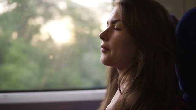 Pensive woman relaxing and looking out of a train window. Side view. Travel, transport concept