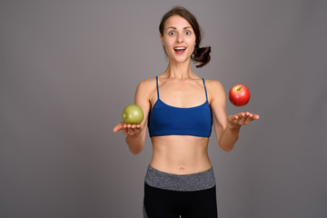 Young beautiful woman ready for gym against gray background