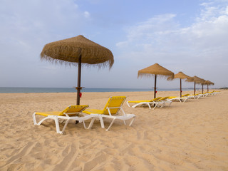 Beach scene with sunbeds and straw umbrella. Summer beach vacation concept