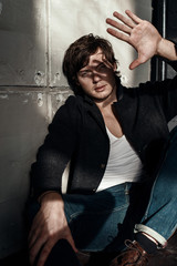 Fashion portrait of handsome man in sweater and jeans over grunge background. Studio shot.