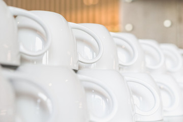 Rows of clean white upside down cups in a cafeteria or restaurant ready to serve a hot beverage