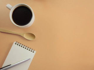 Flat lay a cup of coffee with notebook and pen on beige desk and copy space