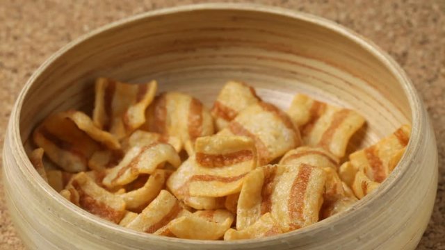 Close up of bacon chips falling into bowl. No sound.