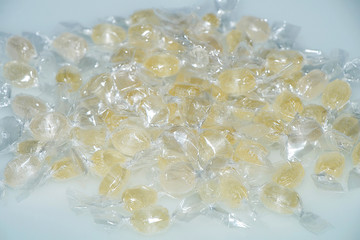 Yellow candy in a transparent wrapper on a white table