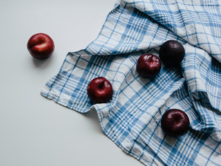 Plums Top view Five whole ripe plums are scattered across a checkered tablecloth Photo template with copy space