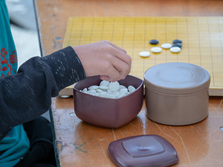 Man juggling white stones while playing Chinese game of Go