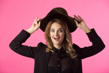 beautiful young joyful girl in a black jacket and hat on a pink background