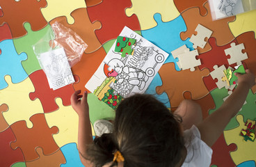 Child girl playing with puzzle over puzzle carpet