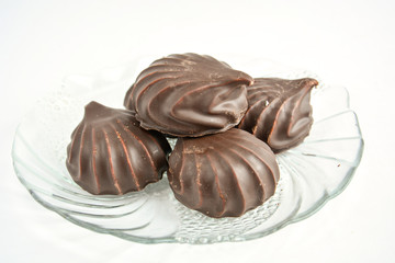 a few marshmallows in chocolate on a transparent dish on a light background