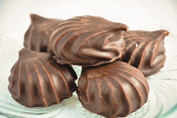 a few marshmallows in chocolate on a transparent dish on a light background