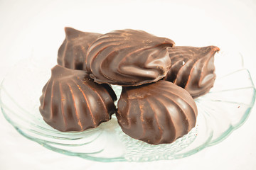 a few marshmallows in chocolate on a transparent dish on a light background