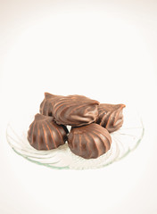 a few marshmallows in chocolate on a transparent dish on a light background