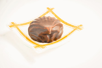 one marshmallow in chocolate on a transparent dish on a light background