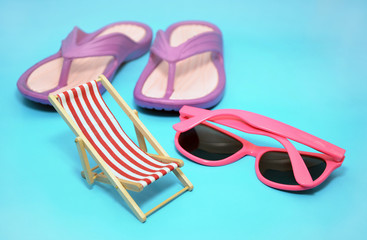 Deckchair with sunglasses and sandals on blue background