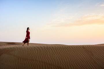 Fototapeta na wymiar Woman walking in the desert at sunset