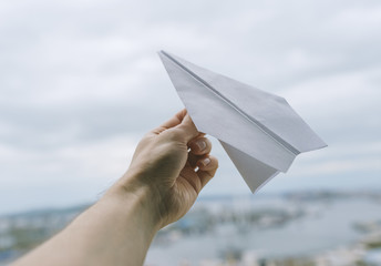 Paper plane in hand on sky background.