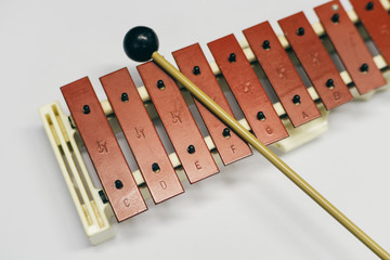 Close up the mini metallophone with a stick on the white background.