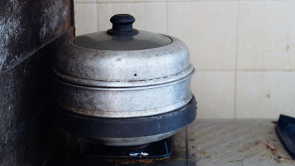 Old stainless Steel Steamer is cooking on the gas stove.