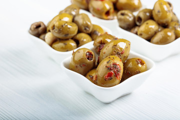 Spiced green olives in oil on a  wooden table.