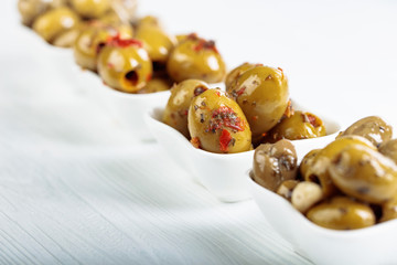 Spiced green olives in oil on a  wooden table.