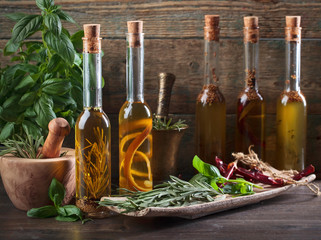 Olive oil with different spices and herbs on a wooden table.
