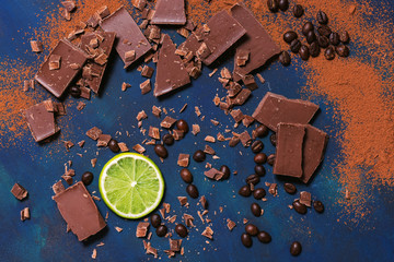 Lime slice with pieces of chocolate and fried coffee beans on a blue background. View from above