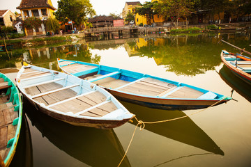 HOI AN, QUANG NAM, VIETNAM, April 26th, 2018: Boats by the river in ancient town Hoi An with view of typical yellow houses