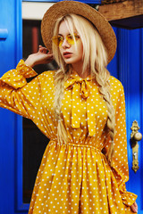 Outdoor portrait of young beautiful fashionable girl wearing trendy yellow color sunglasses, straw...
