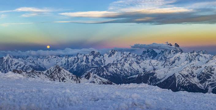 snowy Caucasus mountains at sunset with moonrising and Anticrepuscular rays