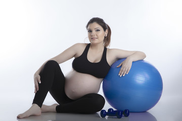Fototapeta na wymiar Pregnant woman is doing exercises with gymnastic ball on white background