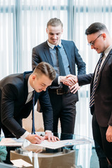 new business partnership. happy smiling man signing contract to become a member of team. men shaking hands