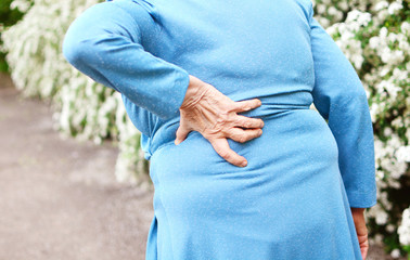 Backache. Aged woman with back pain. Elderly woman goes to doctor. .