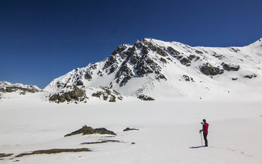 Fototapeta na wymiar man standing on snow field in mountains at daylight