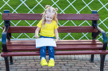 little girl draws in the park on the bench. concept of children's creativity