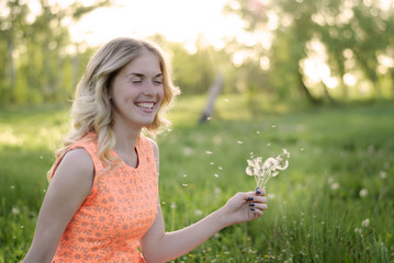 Fototapeta na wymiar Beauty blond model girl and smelling dandelion flowers. Allergy free. Healthy Smiling Girl portrait