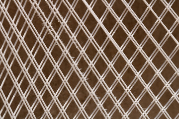 The diagonal interweaving of white threads on a brown background.