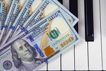 Hundred dollar bills of a new sample lie in a fan shaped on piano keyboard