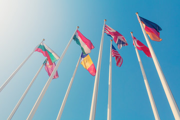 Bottom view of a flags of different countries of the world against a sunlight in the clear blue sky (toned)