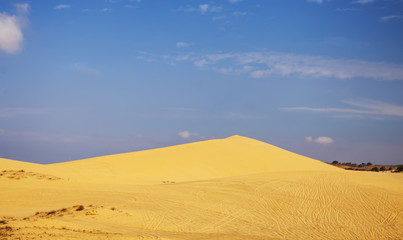 Sand dunes near Mui Ne. Group of off roads on top of dunes in the background. Sunny day with blue sky and clouds