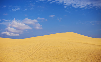 Sand dunes near Mui Ne. Group of off roads on top of dunes in the background. Sunny day with blue sky and clouds