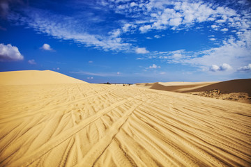 Sand dunes near Mui Ne. Group of off roads on top of dunes in the background. Sunny day with blue sky and clouds