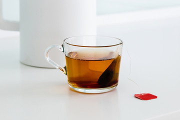 A cup of black tea stands on a white table