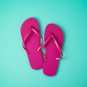 Pink flip flops over blue background.