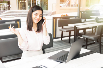 Fototapeta premium Young pretty woman speaking on mobile phone and sitting in cafe with notebook.