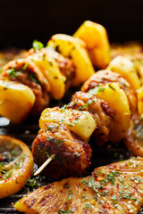 Grilled skewers with pineapple and chicken meat with herbs on a grill plate. Fruit and meat skewers