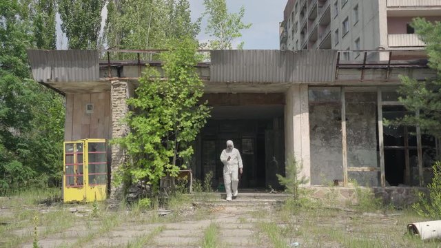 Man using a geiger counter with gas mask and protective suit in Pripyat. Slider shot - Juni 2017: 30km Chernobyl, exclusion zone