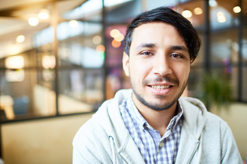 Fototapeta premium Young creative businessman in casualwear looking at camera by his workplace in modern office